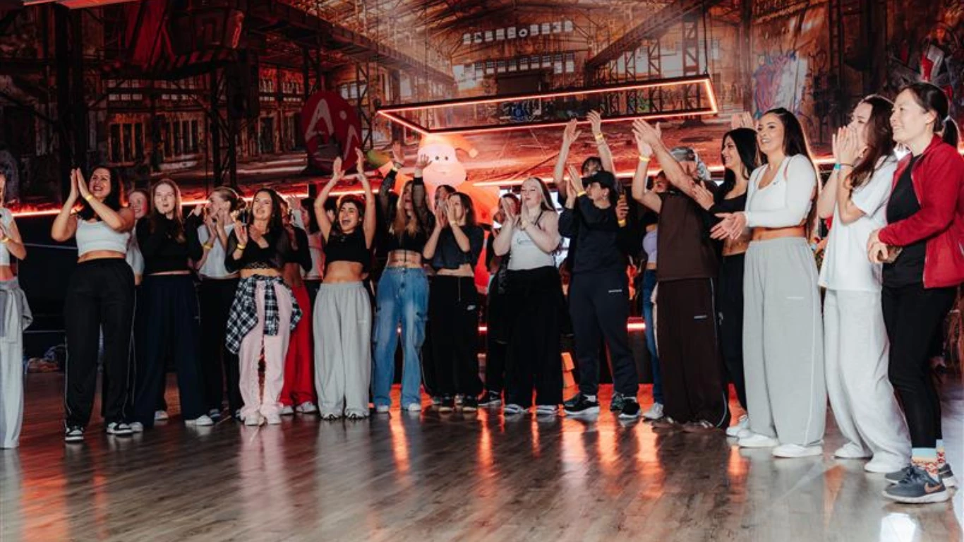 Gruppe von Menschen im Kursraum, die im Kreis stehen und gemeinsam klatschen