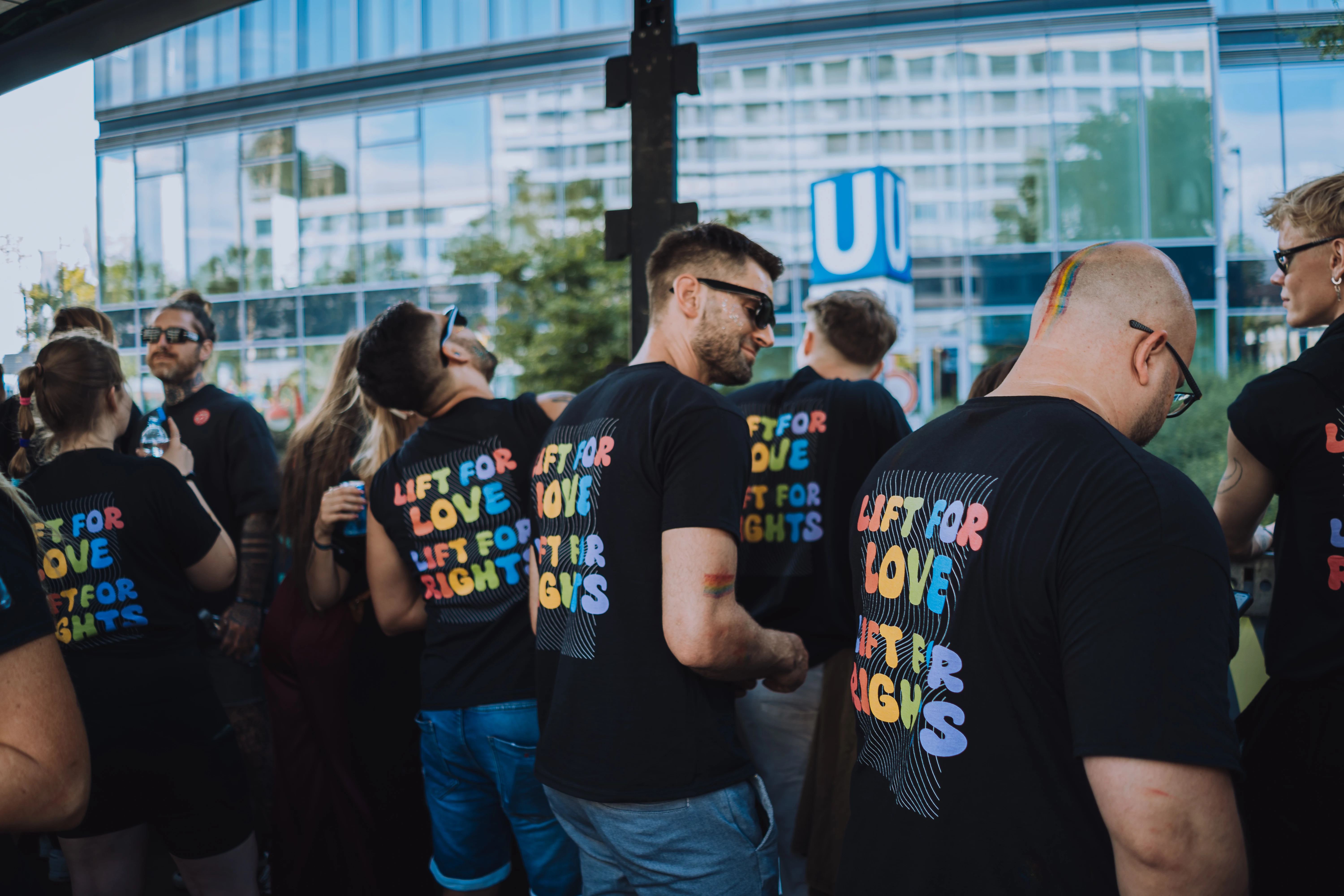 Gruppe von Menschen in schwarzen T-Shirts mit bunter Aufschrift Lift for Love, Lift for Rights bei einer Veranstaltung im Freien