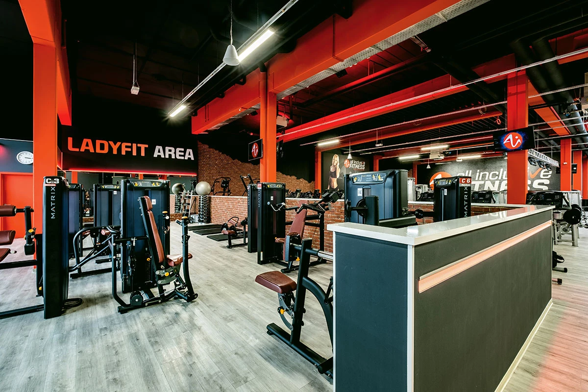 Ladyfit Area im Fitnessstudio mit verschiedenen Trainingsmaschinen. Der Bereich ist modern gestaltet mit roten Säulen, grauem Boden und einem ‚Ladyfit Area‘-Schild an der Wand