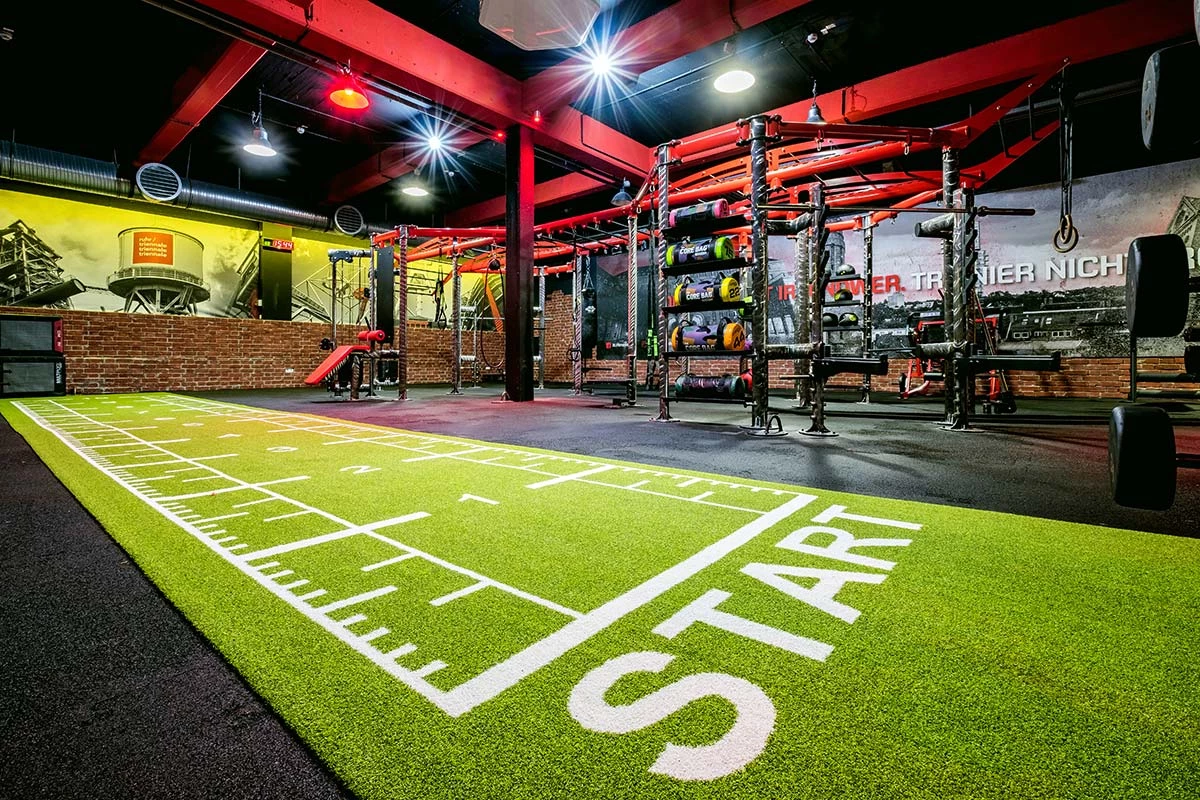 Moderne Functional Area mit grünem Kunstrasen und Trainingsstationen für funktionelles Training im Fitnessstudio
