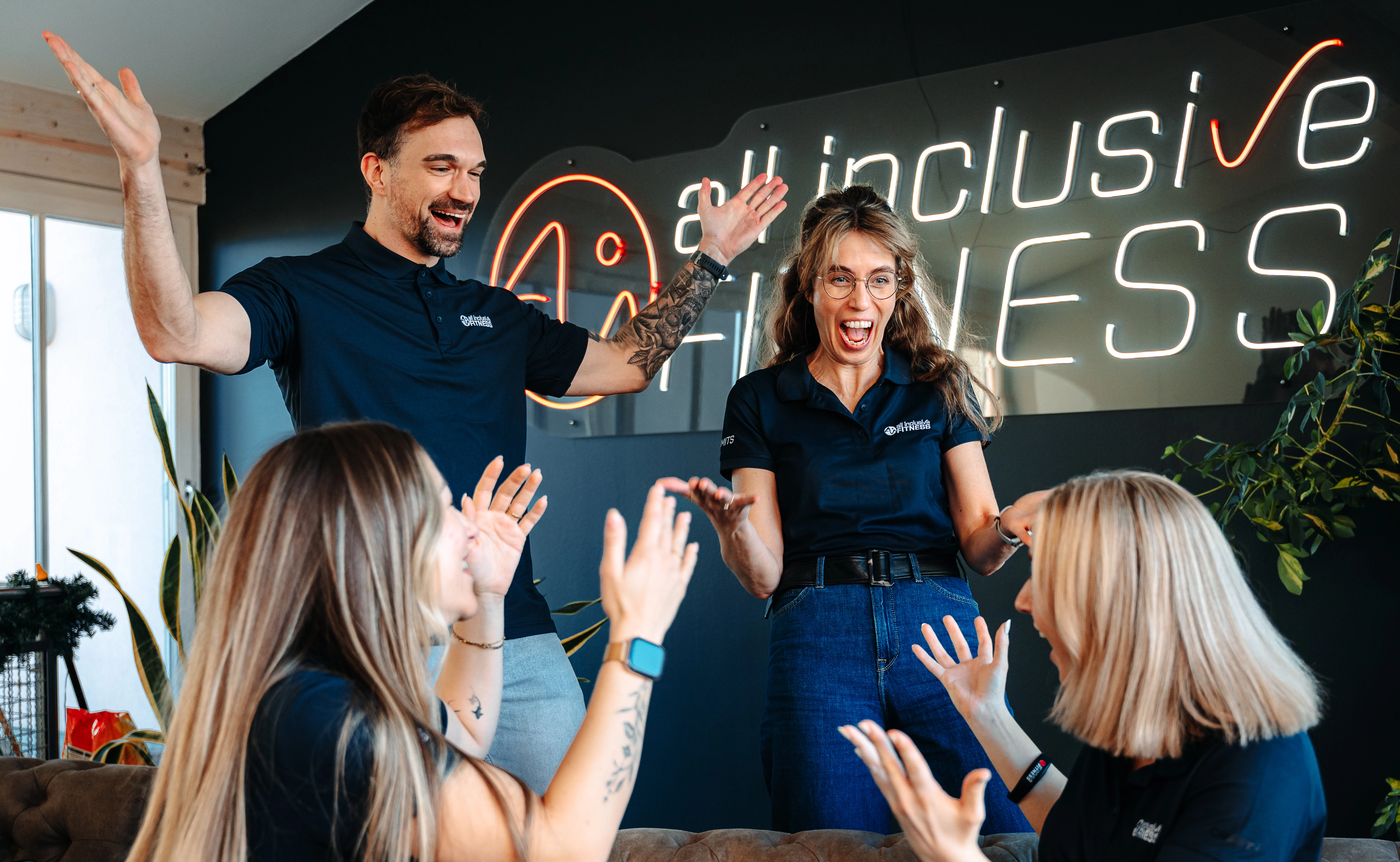 Frau und Mann sitzen auf Trainingsgeräten im Fitnessstudio und geben sich ein High Five.