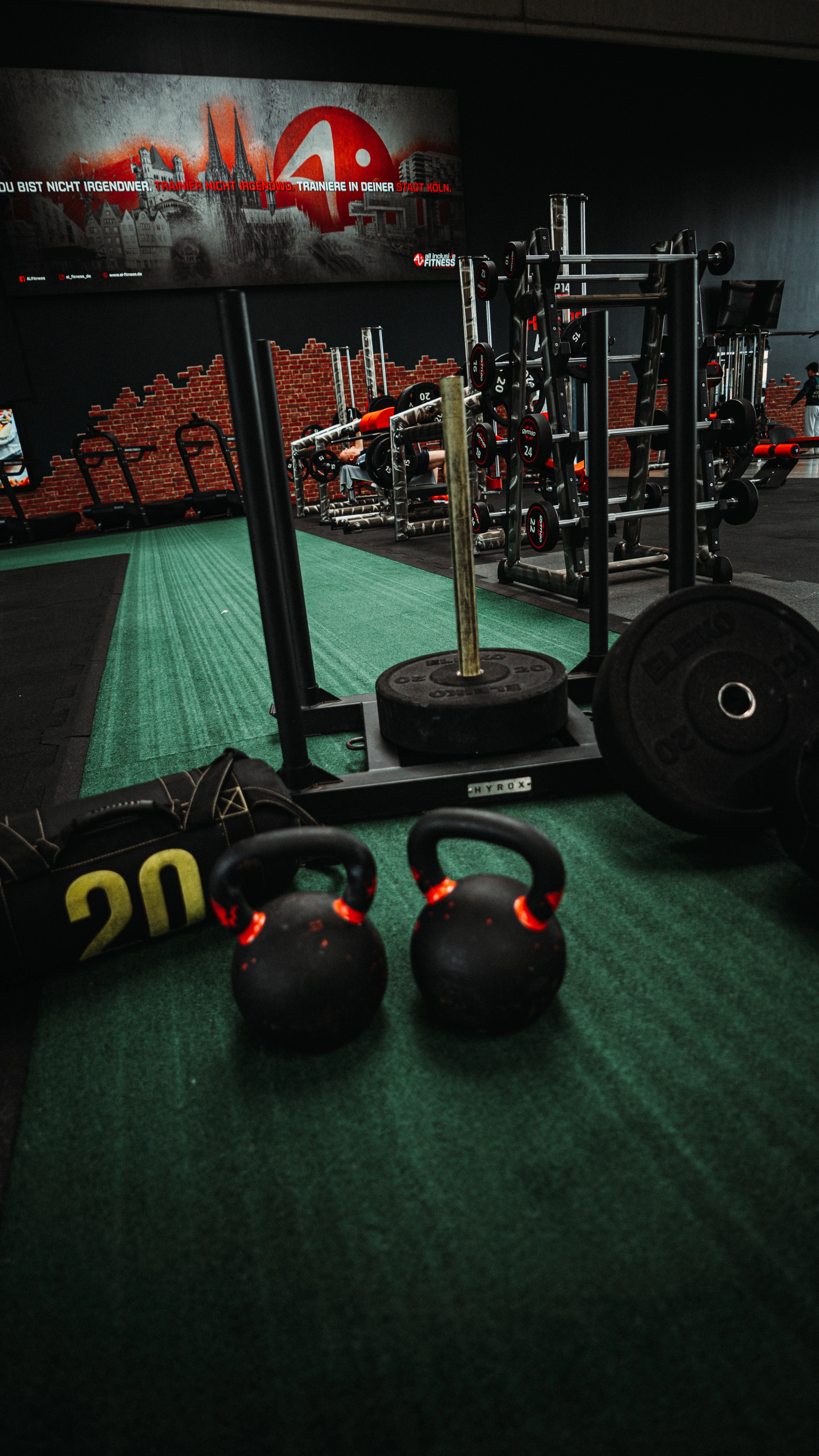 Gewichte und Trainingsgeräte im Fitnessstudio. Text: ‚HYROX Partner – all inclusive Fitness ist HYROX Partner im Raum Köln und exklusiver Titelpartner auf der Fibo