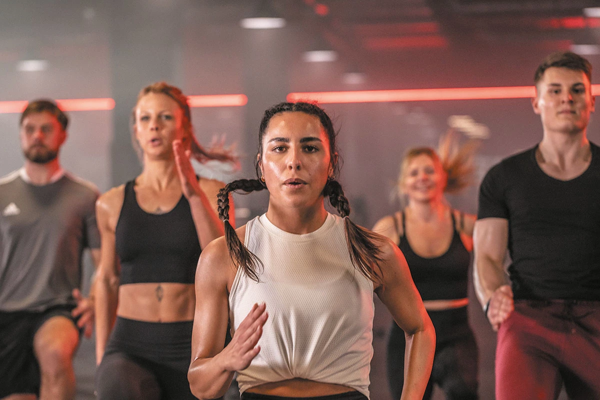 Dynamisches Gruppentraining mit Fokus auf Ausdauer und Bewegung im Kursraum eines Fitnessstudios