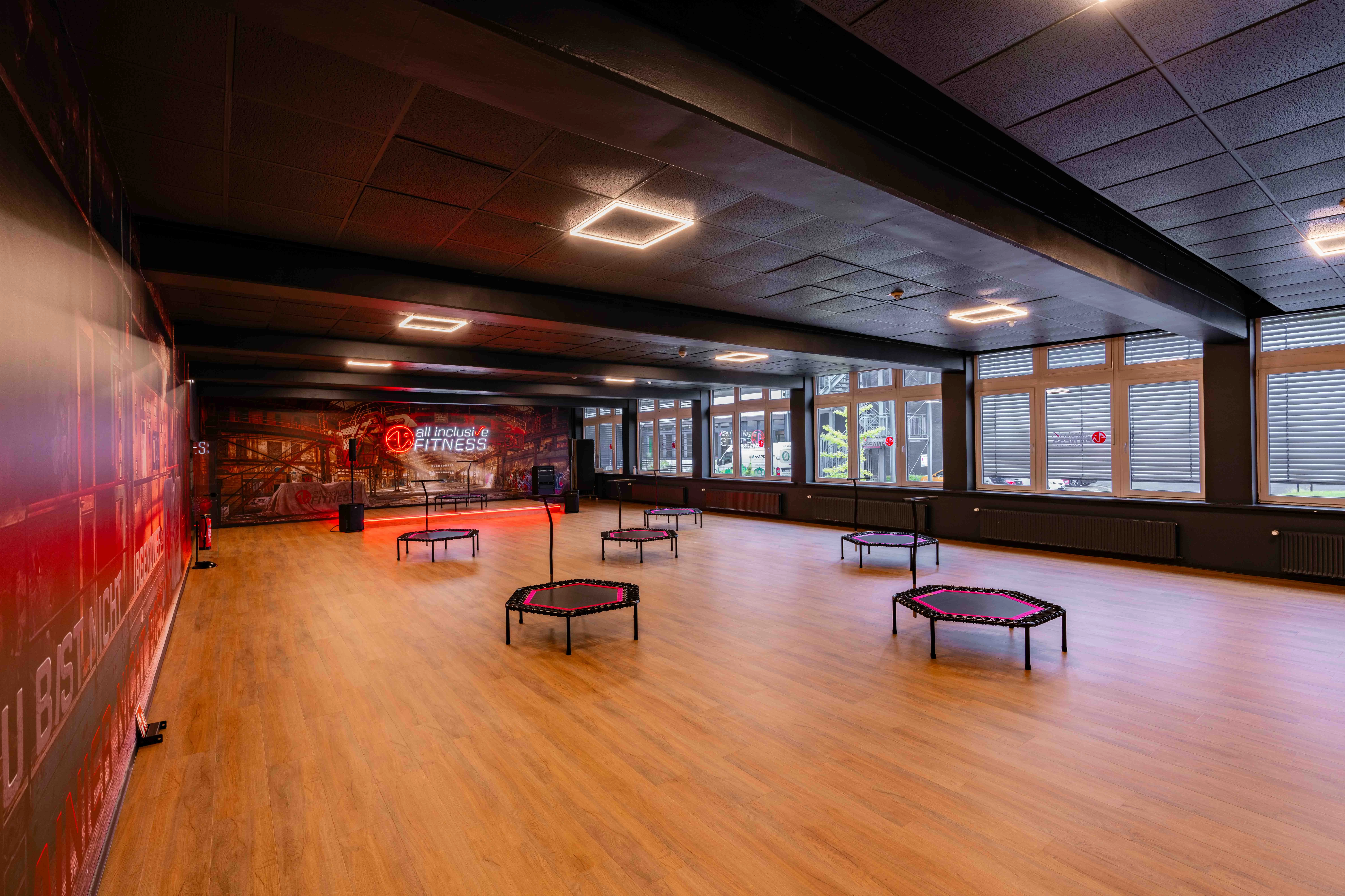 Moderner Kursraum mit mehreren kleinen Fitness-Trampolinen auf hellem Holzfußboden
