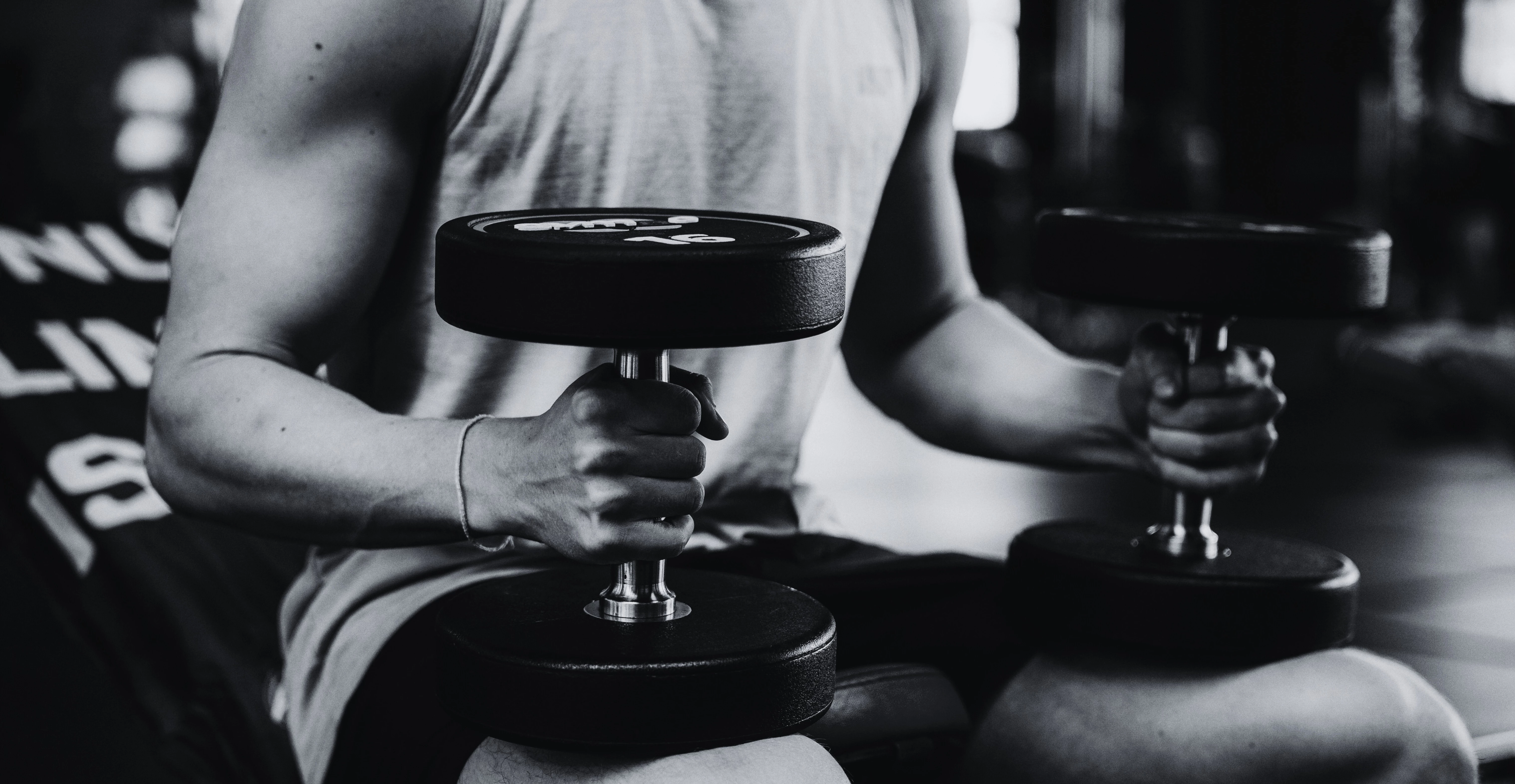 Mann mit Hanteln auf dem Bein im Fitnessstudio